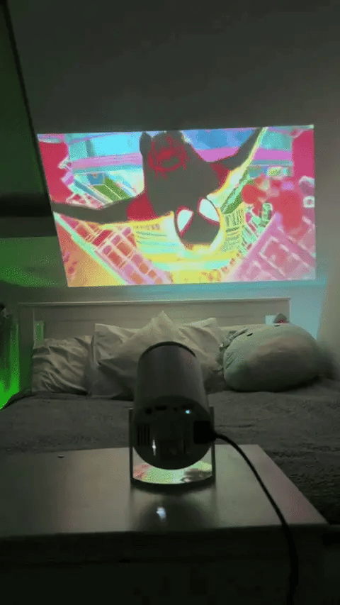 A movie projected large above a bed in a dark bedroom